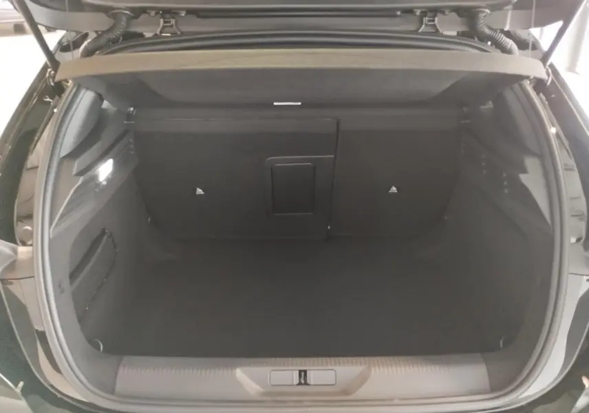 Coffre ouvert de la Peugeot 308 noire métallisée, vue arrière montrant l'espace de chargement vide et les dossiers rabattables.