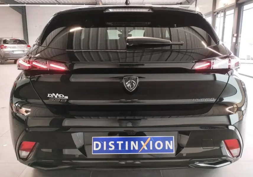 Vue arrière d'une Peugeot 308 hybride noire métallisée avec feux arrière LED en forme de griffes et logo lion central.