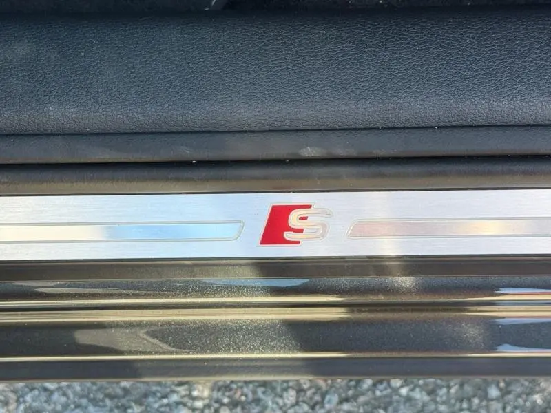 Gros plan sur la plaque de seuil de porte avec logo S rouge sur Audi Q2 35 TDI S line gris Daytona nacré.
