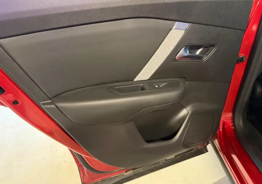 Vue rapprochée de la porte arrière gauche rouge d'une Citroën C4 X 2021, avec garniture noire et insert gris texturé.