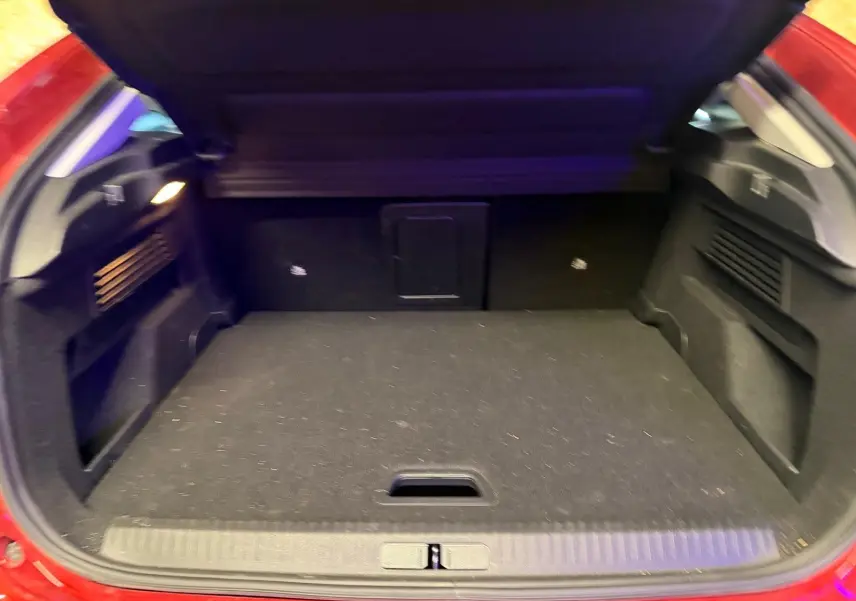 Coffre ouvert vu de l'arrière d'une Citroën C4 X rouge, montrant un espace de chargement noir et bien agencé.