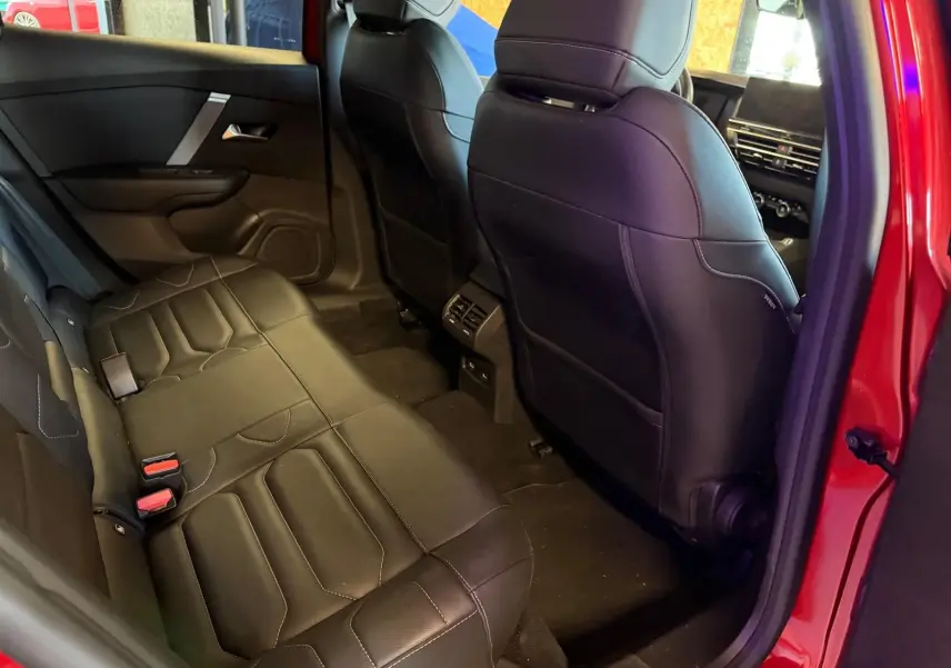 Vue intérieure côté gauche des sièges arrière en cuir noir du Citroën C4 X rouge, avec ventilation arrière visible.