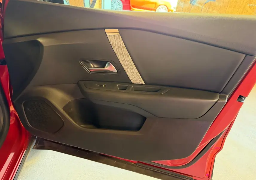 Intérieur de la porte côté gauche rouge de la Citroën C4 X 2021, avec panneau noir et poignée argentée.