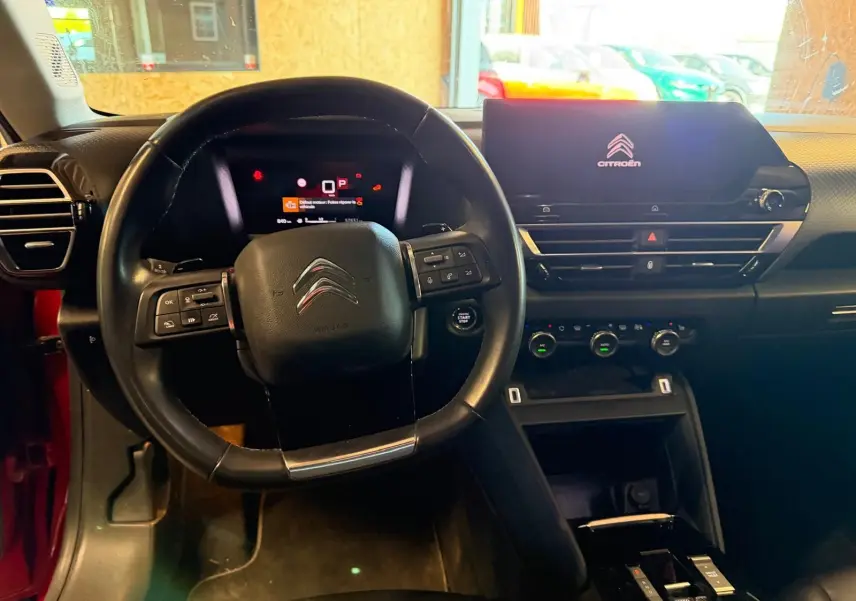 Vue intérieure du poste de conduite de la Citroën C4 X 1.5 BlueHDi 130, tableau de bord et volant noir.