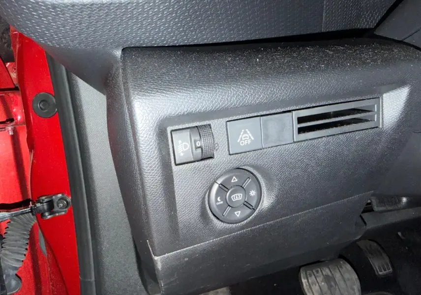 Détail du tableau de bord côté gauche noir du Citroën C4 X rouge, avec commandes d’éclairage et ventilation.