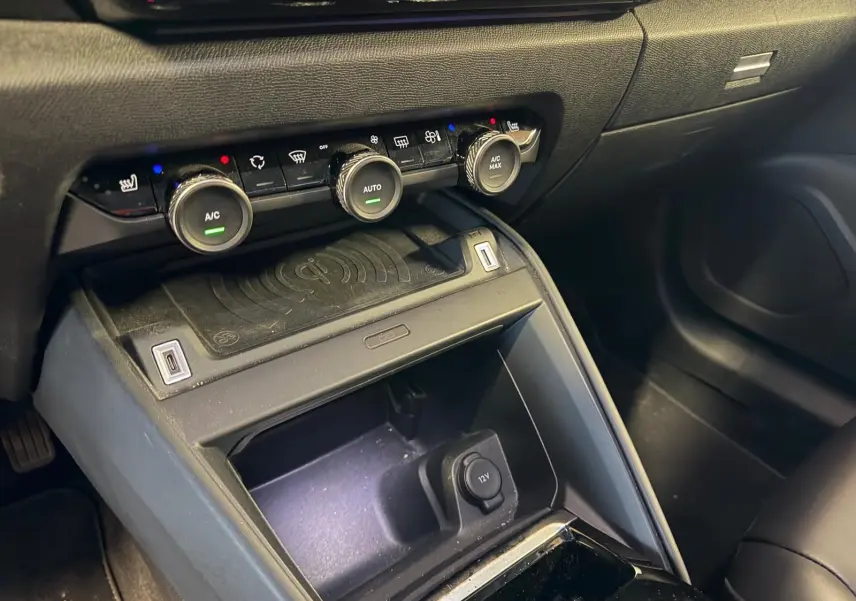 Vue rapprochée de la console centrale noire du Citroën C4 X 2021, avec commandes climatisation et prise 12V visible.