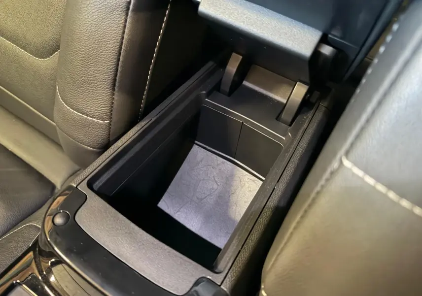 Vue rapprochée de la console centrale ouverte avec rangement intérieur en plastique noir sur Citroën C4 X 2021.