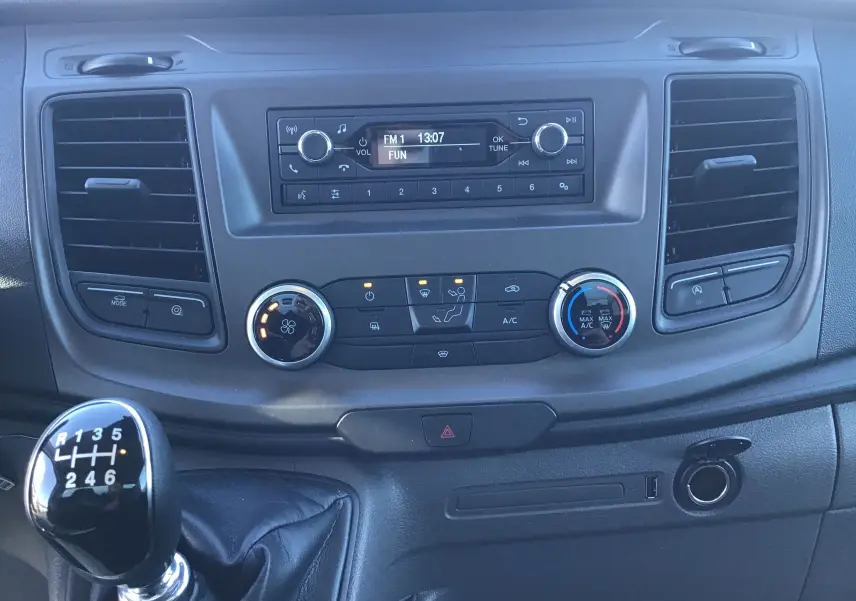 Vue rapprochée du tableau de bord noir du Ford Transit Chassis Cabine 2024 avec levier de vitesses manuel et commandes climatisation.