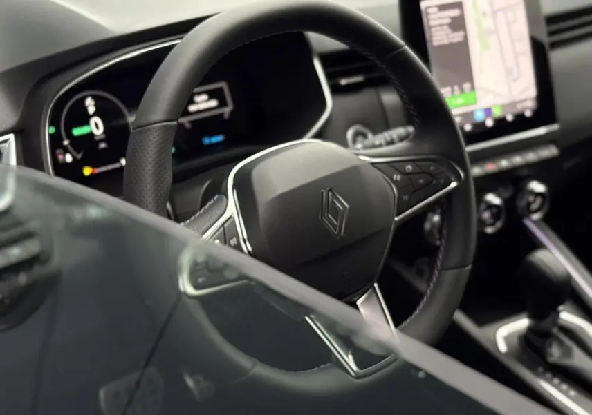 Vue rapprochée du volant multifonction noir et tableau de bord numérique de la Renault Clio hybride 2025.