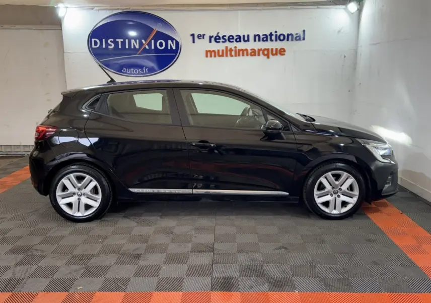 Profil côté gauche d'une Renault Clio Business E-Tech hybride noire 2021, stationnée en intérieur sur sol gris et orange.