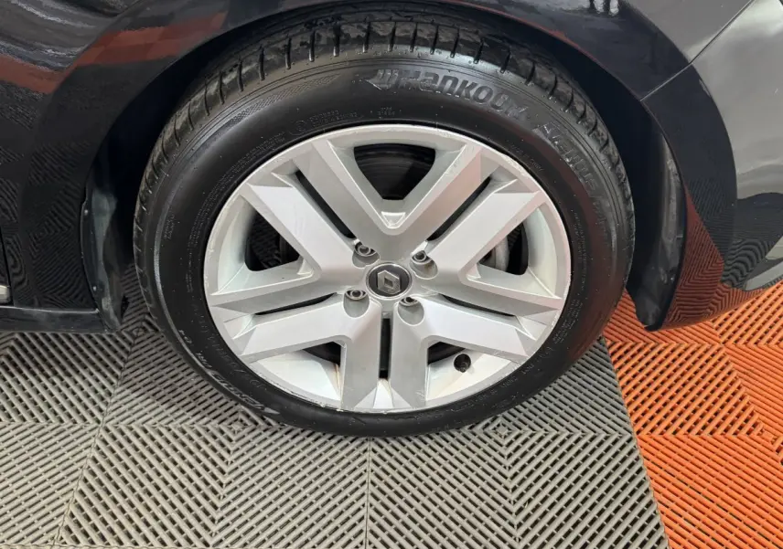 Gros plan sur la roue avant droite d'une Renault Clio Business E-Tech noire, avec jante alliage argentée et pneu Hankook.