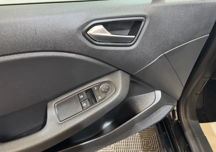 Vue rapprochée de la porte avant gauche noire de la Renault Clio Business E-Tech hybride avec commandes électriques des vitres.