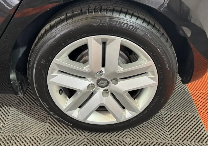 Gros plan sur la roue avant droite noire d’une Renault Clio Business E-Tech hybride 2021 avec jante argentée à cinq branches.