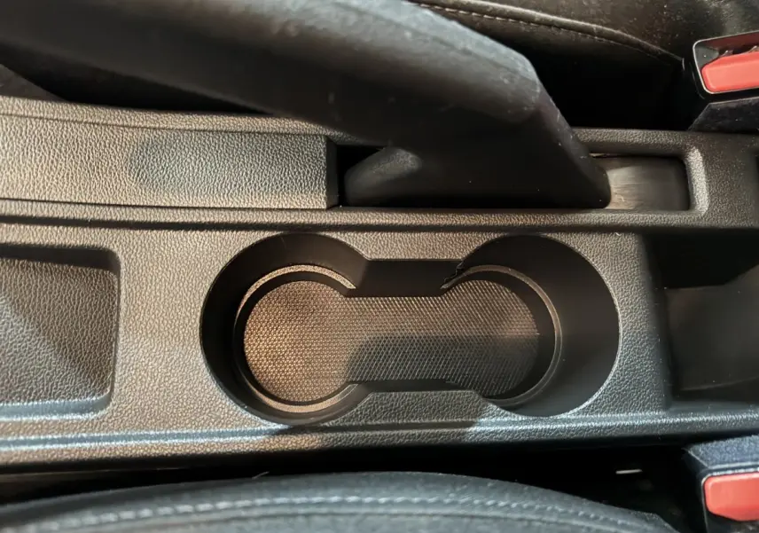 Gros plan sur les porte-gobelets noirs et le frein à main central de la Renault Clio Business E-Tech hybride 2021.