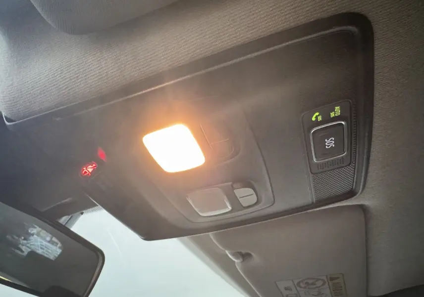 Plafonnier allumé avec bouton SOS et témoin de ceinture, vue intérieure avant d'une Renault Clio noire hybride.