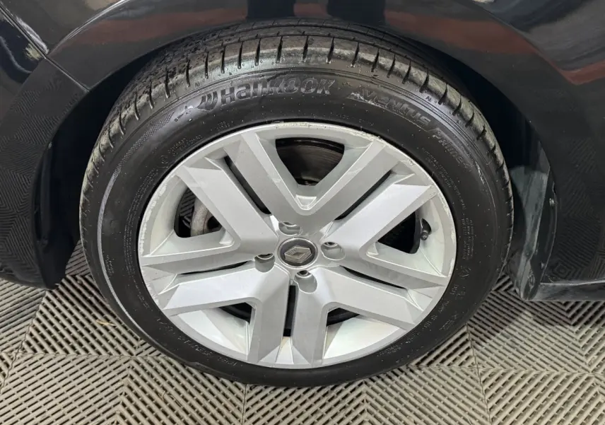 Gros plan sur la roue avant droite noire d’une Renault Clio Business E-Tech hybride 2021 avec jante argentée à cinq branches.