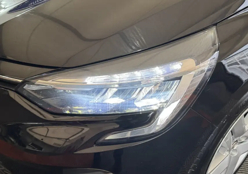 Gros plan sur le phare avant droit LED d'une Renault Clio Business E-Tech hybride noire, soulignant ses lignes modernes.