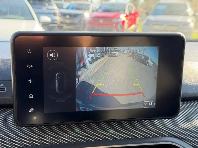 Écran de caméra de recul du Dacia Jogger 2025 montrant la vue arrière avec lignes de guidage colorées sur route urbaine.