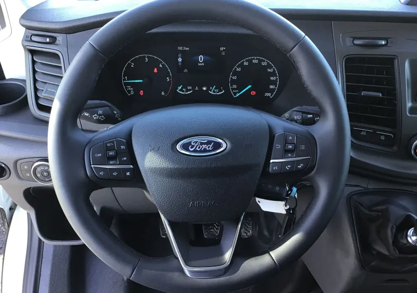Vue rapprochée du volant Ford noir avec commandes intégrées et tableau de bord numérique du Transit Chassis Cabine 2024.