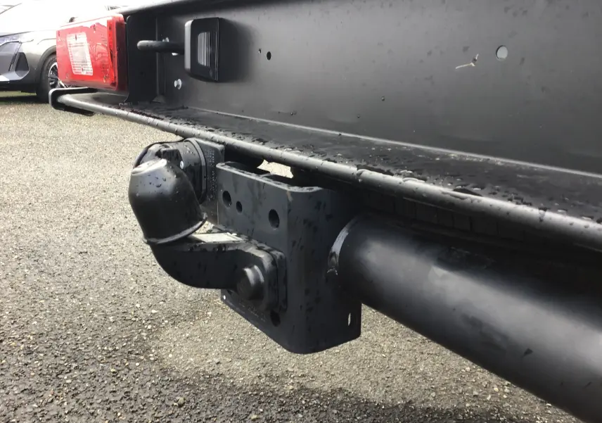 Gros plan sur l'attelage noir et la benne arrière du Ford Transit Châssis Cabine blanc, vue côté gauche arrière.