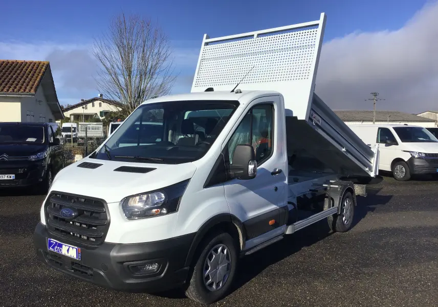 Ford Transit Chassis Cabine blanc en 3/4 avant droit avec benne relevée sur parking extérieur.