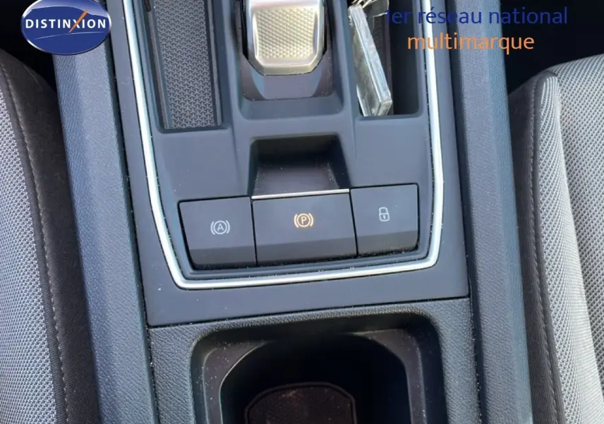 Gros plan sur la console centrale de la SEAT LEON 2025, avec boutons de frein à main électronique et rangement, intérieur gris.