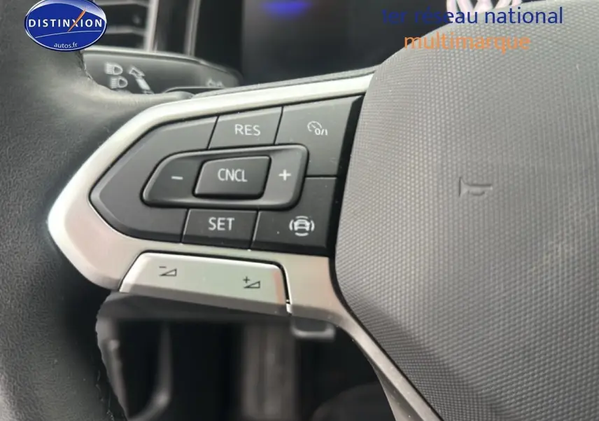 Gros plan sur les commandes au volant côté gauche d’une Volkswagen Polo gris cendre, intérieur moderne et fonctionnel.