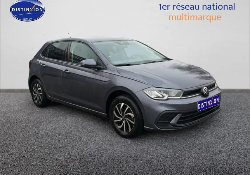 Volkswagen Polo gris cendre vue 3/4 avant droit sur sol gris avec calandre noire et jantes alliage.