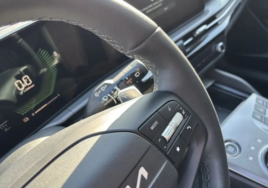 Gros plan sur le volant cuir multifonctions du Kia Sportage 1.6 T-GDI HEV 239 EX avec tableau de bord numérique.