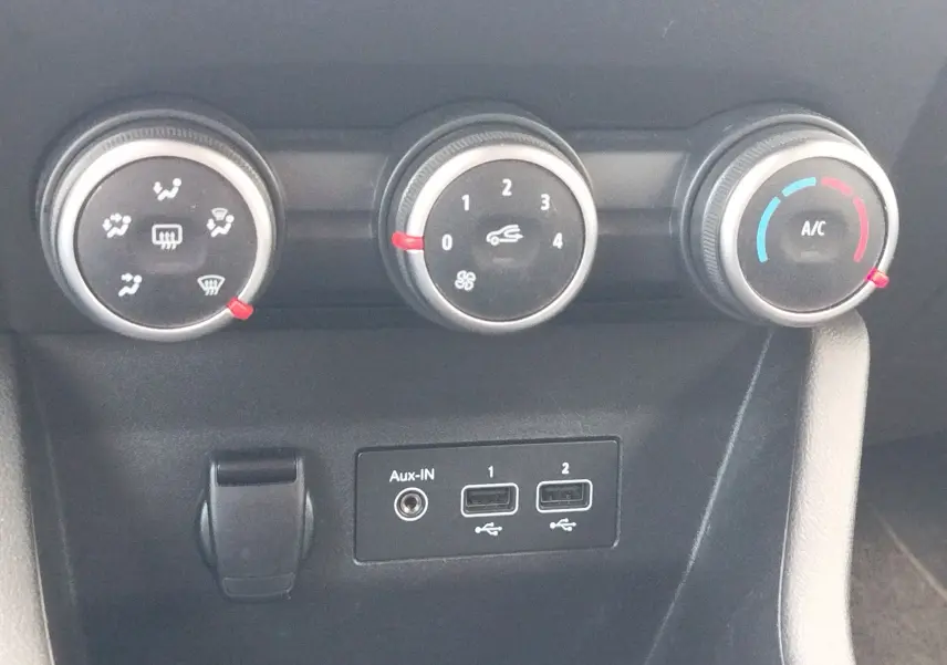 Vue rapprochée des commandes de climatisation et des ports USB sur la console centrale d’une Renault Clio 2022.