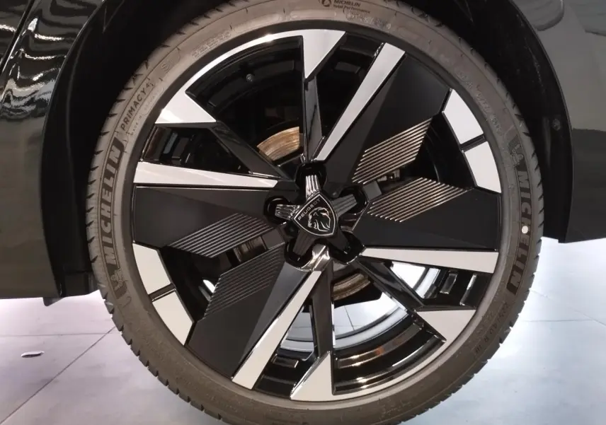 Gros plan sur la jante alliage 18" bi-ton noir et argent du Peugeot 308 noir métal, avec logo lion central.