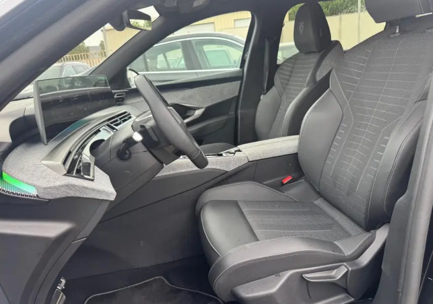 Vue intérieure côté conducteur du Peugeot 5008 Hybrid 145 ch e-DCS6 GT 2025, sièges noirs et tableau de bord numérique.