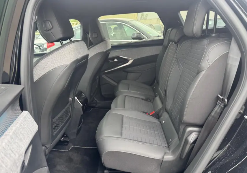 Vue intérieure côté droit des sièges arrière en cuir noir et tissu gris du Peugeot 5008 Hybrid 2025, avec porte ouverte.