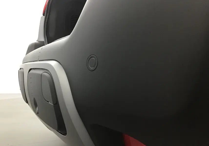 Gros plan sur le pare-chocs arrière gris platinium et noir du Citroën C3 Aircross 2024 avec capteur de recul visible.