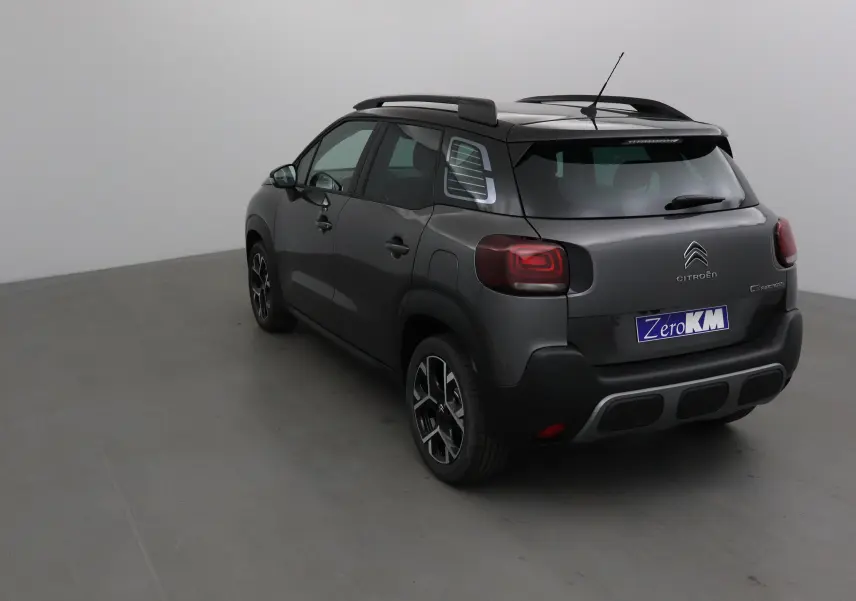 Vue 3/4 arrière droite d'un Citroën C3 Aircross gris platinium et noir avec barres de toit et feux arrière LED.
