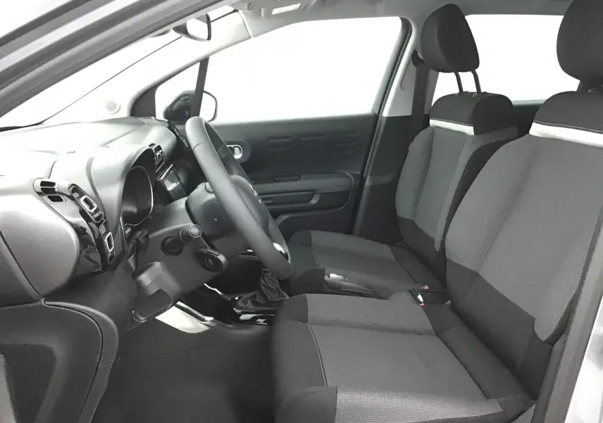 Vue intérieure côté conducteur de la Citroën C3 Aircross 2024 avec sièges gris et tableau de bord noir.