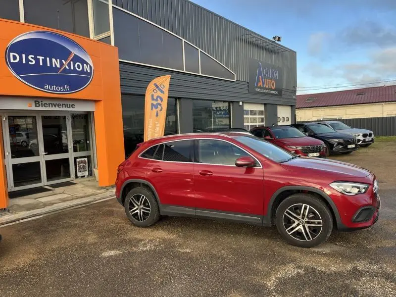 Mercedes GLA 200 Business Line rouge Patagonie métallisé, vue profil côté gauche devant un garage avec enseigne orange