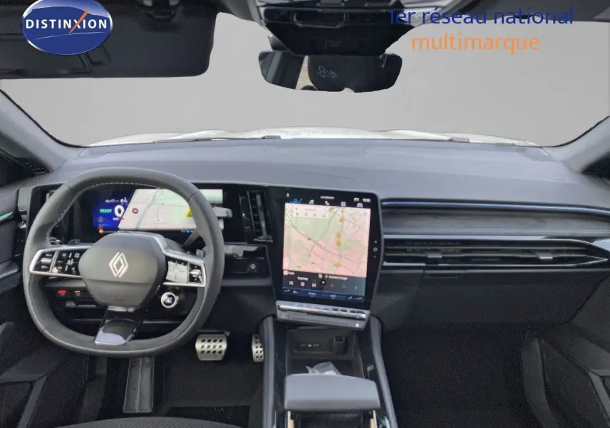 Vue intérieure avant du Renault Austral blanc nacré, tableau de bord moderne avec écran tactile central affichant une carte.