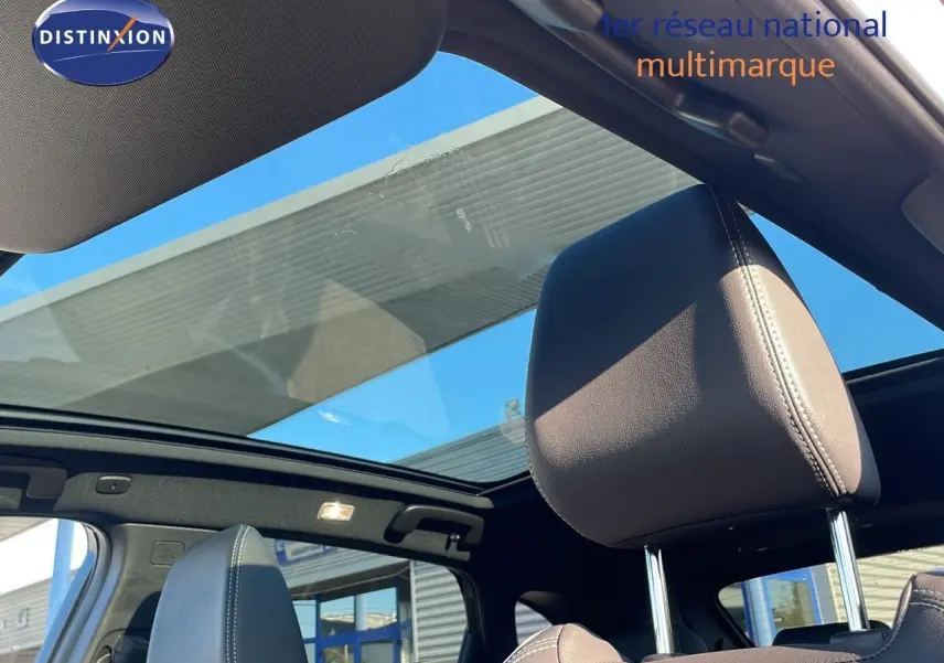 Vue intérieure du Nissan Qashqai 2025 avec toit panoramique en verre et appuie-tête en cuir noir visible côté gauche.