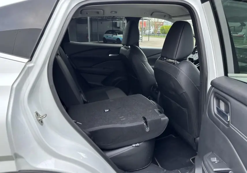 Vue côté gauche arrière du Nissan Qashqai blanc nacré avec banquette arrière rabattue et sellerie noire mixte TEP et tissu.