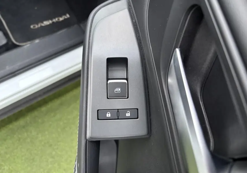 Gros plan sur les commandes de verrouillage et lève-vitre côté conducteur du Nissan Qashqai blanc nacré 2025.