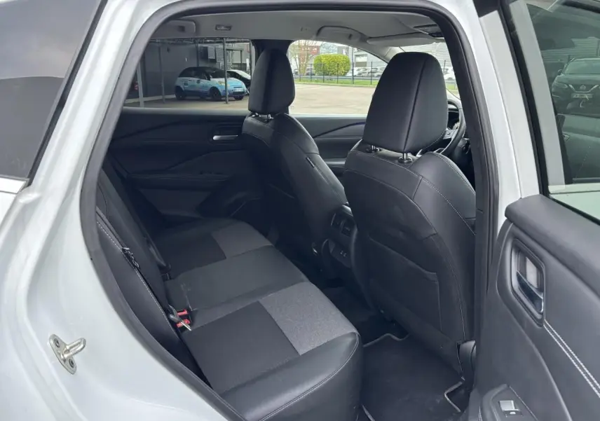 Vue intérieure côté gauche de la banquette arrière noire et grise du Nissan Qashqai blanc nacré 2025, portes ouvertes.