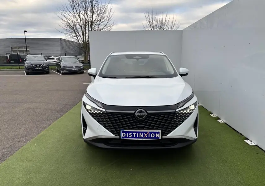 Vue de face du Nissan Qashqai blanc nacré avec calandre noire texturée et phares LED allumés.