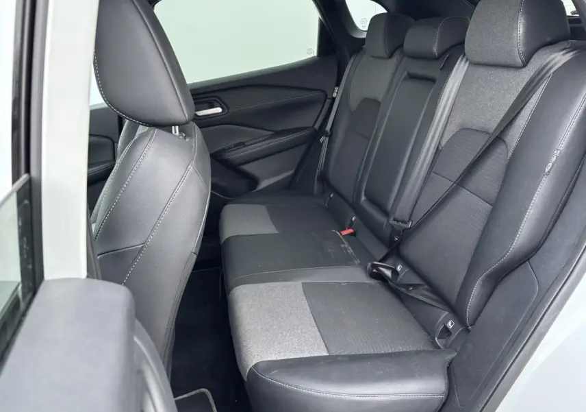 Vue intérieure côté gauche sur la banquette arrière mixte cuir et tissu noir du Nissan Qashqai blanc nacré 2025.