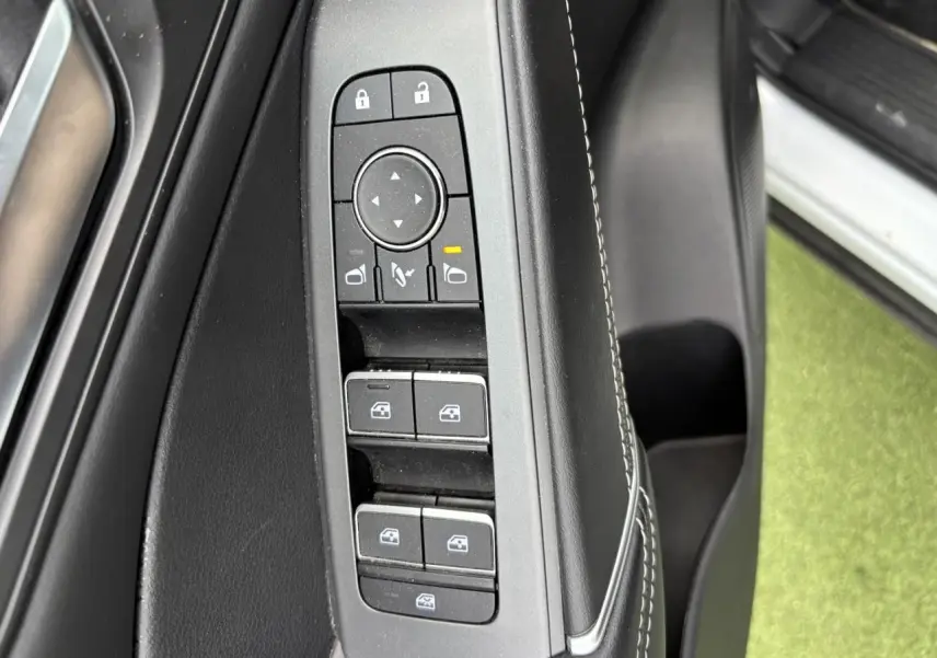 Gros plan sur les commandes de lève-vitres et rétroviseurs côté gauche intérieur du Nissan Qashqai blanc nacré 2025.