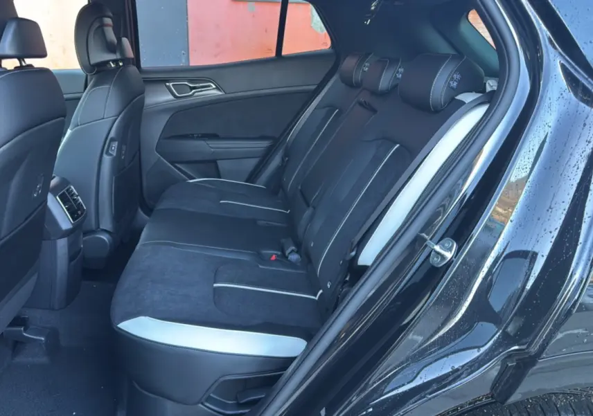 Vue intérieure côté droit sur la banquette arrière noire et grise du Kia Sportage 2026 avec porte ouverte et sellerie mixte cuir/alcantara.