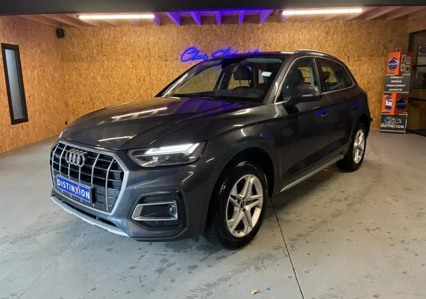 Audi Q5 gris en 3/4 avant droit, avec calandre large et jantes en alliage à 5 branches doubles.