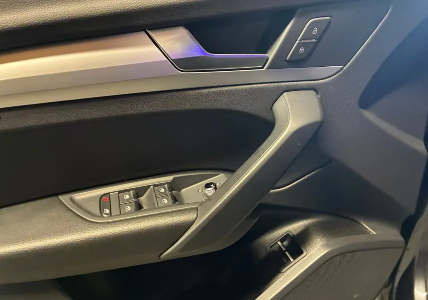 Vue rapprochée de la porte avant gauche de l'Audi Q5 2024 grise, montrant les commandes de vitres et verrouillage.
