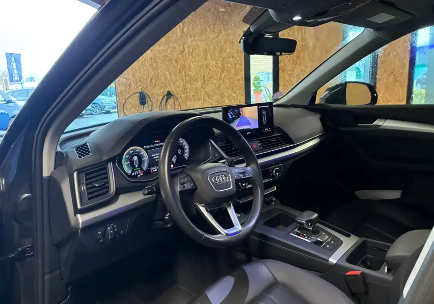 Vue intérieure côté conducteur de l'Audi Q5 2024, tableau de bord noir avec écran central et volant multifonction.