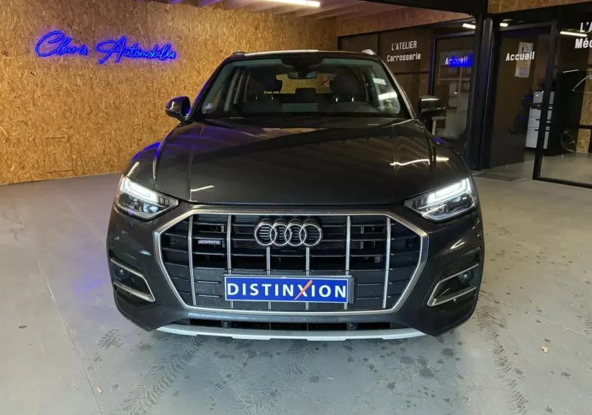 Vue frontale d'un Audi Q5 gris avec calandre imposante et phares LED allumés dans un garage.